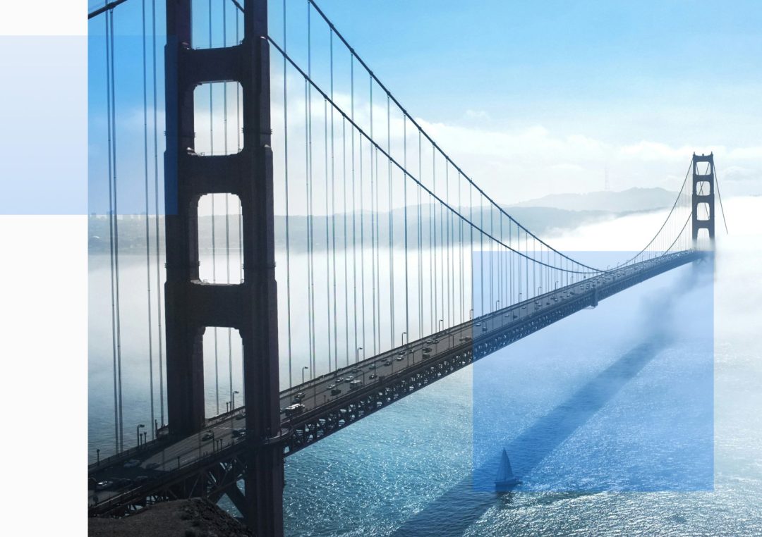 Golden Gate Bridge stretching through thick morning fog with visible car traffic and a sailboat below, symbolizing smart mobility and safe driving infrastructure